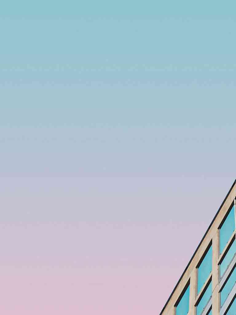 Low-angle view of a modern office building against a blue and pink sky.
